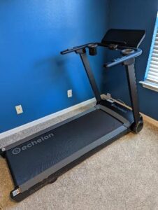Peloton treadmill unplugged from the wall outlet in a blue colored room